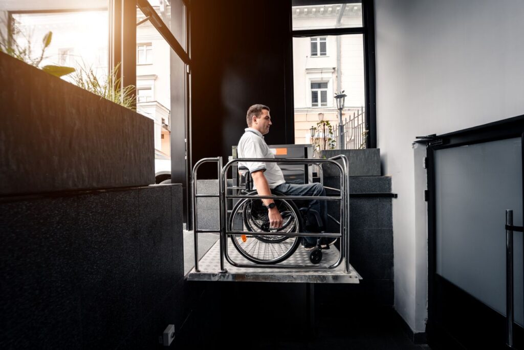Rollstuhlfahrer nutzt Plattformlift in Gebäudezugang, barrierefreier Zugang durch vertikale Hebetechnik in moderner Architektur